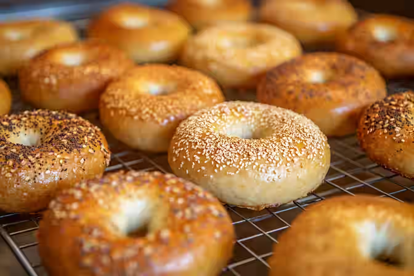 Freshly baked protein bagels recipe with sesame seeds on a cooling rack.